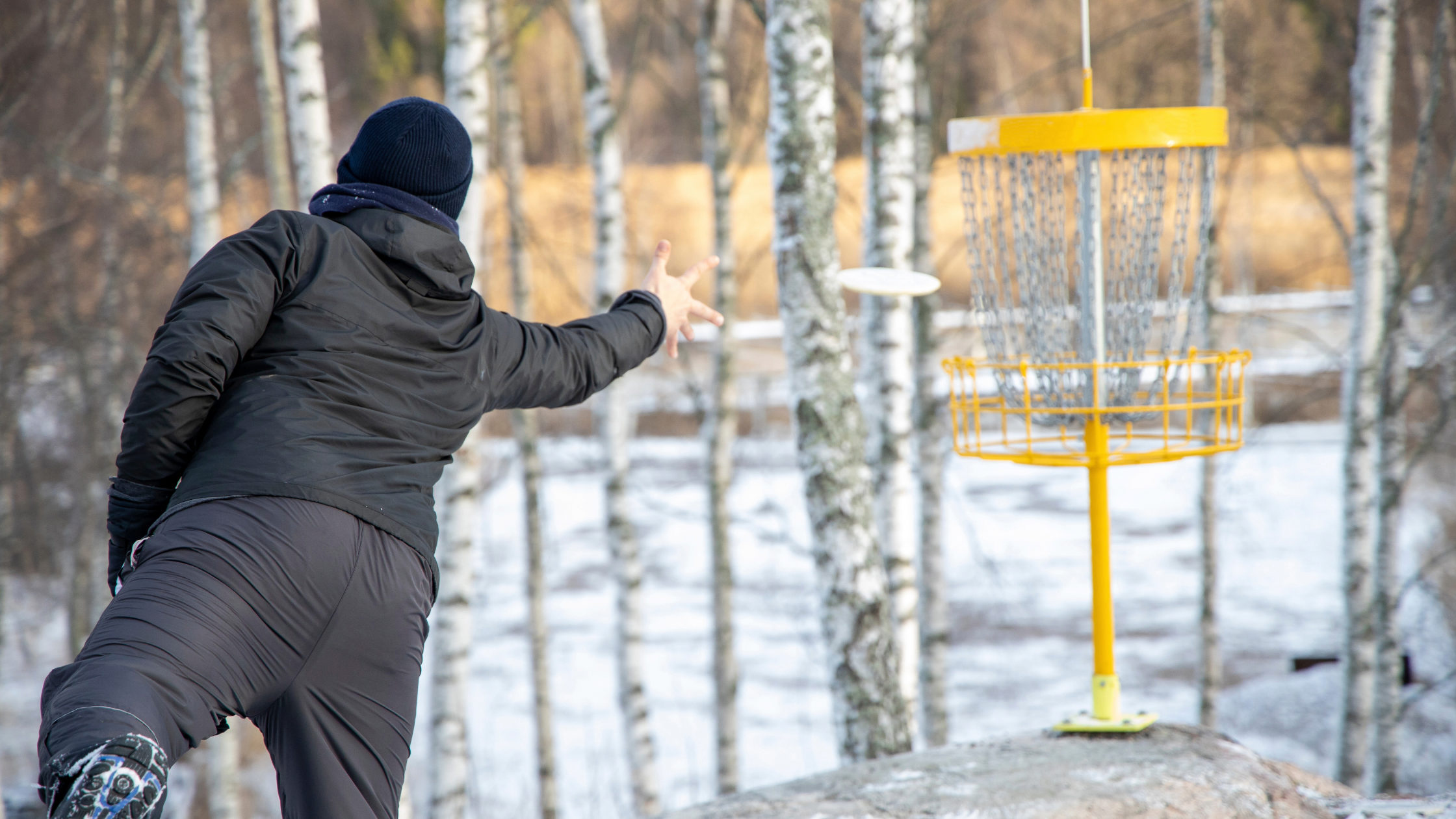 disc golfer hitting putt in the winter